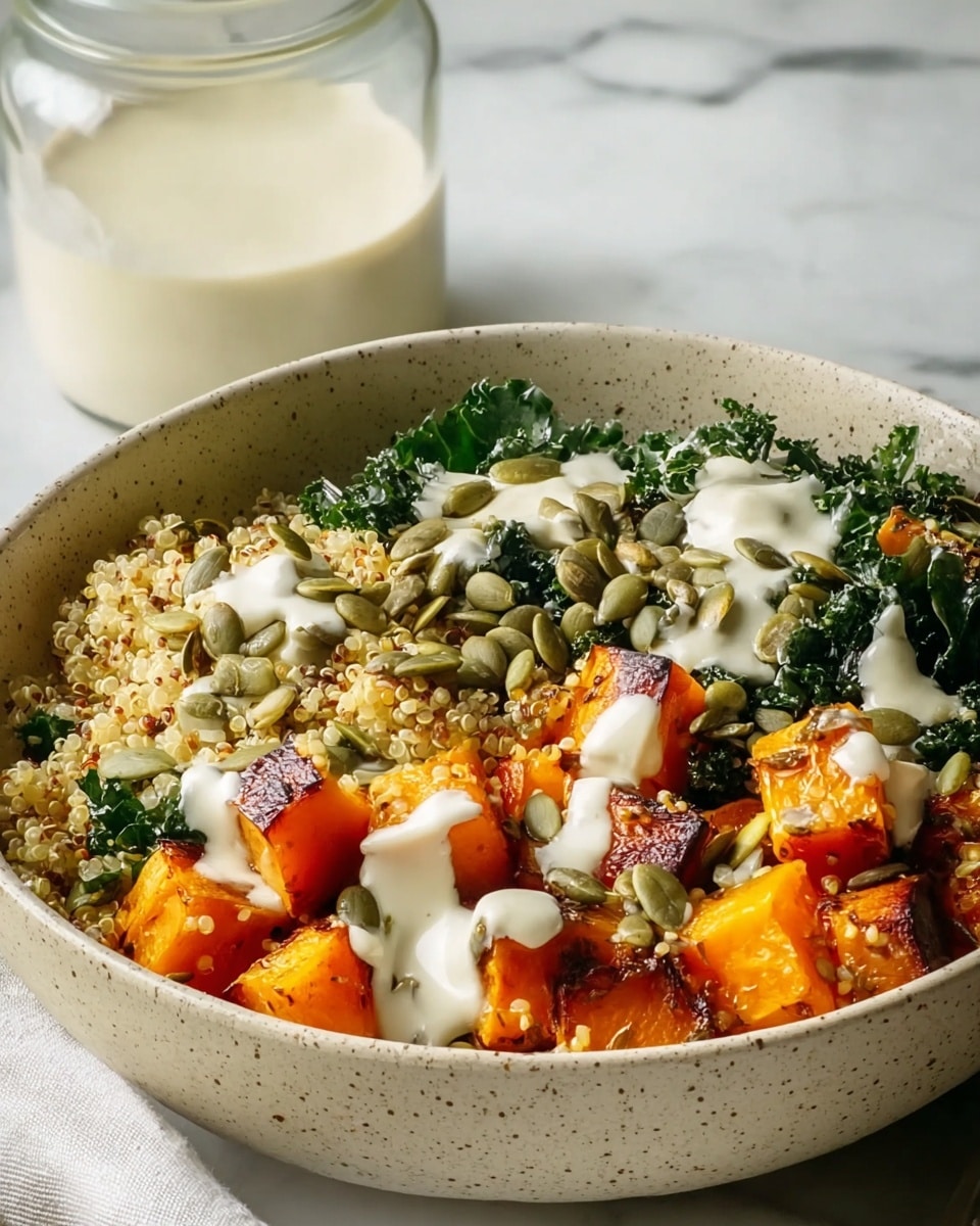 A beige speckled bowl filled with three main layers: the bottom layer consists of bright orange roasted butternut squash cubes with a slightly crispy texture, the middle layer is made up of light yellow quinoa grains mixed with dark green chopped kale, and the top layer is scattered with green pumpkin seeds. The dish is drizzled with a creamy white sauce over the squash and quinoa. The bowl sits on a white marbled surface, with a glass jar filled with a similar creamy white liquid blurred in the background. photo taken with an iphone --ar 4:5 --v 7