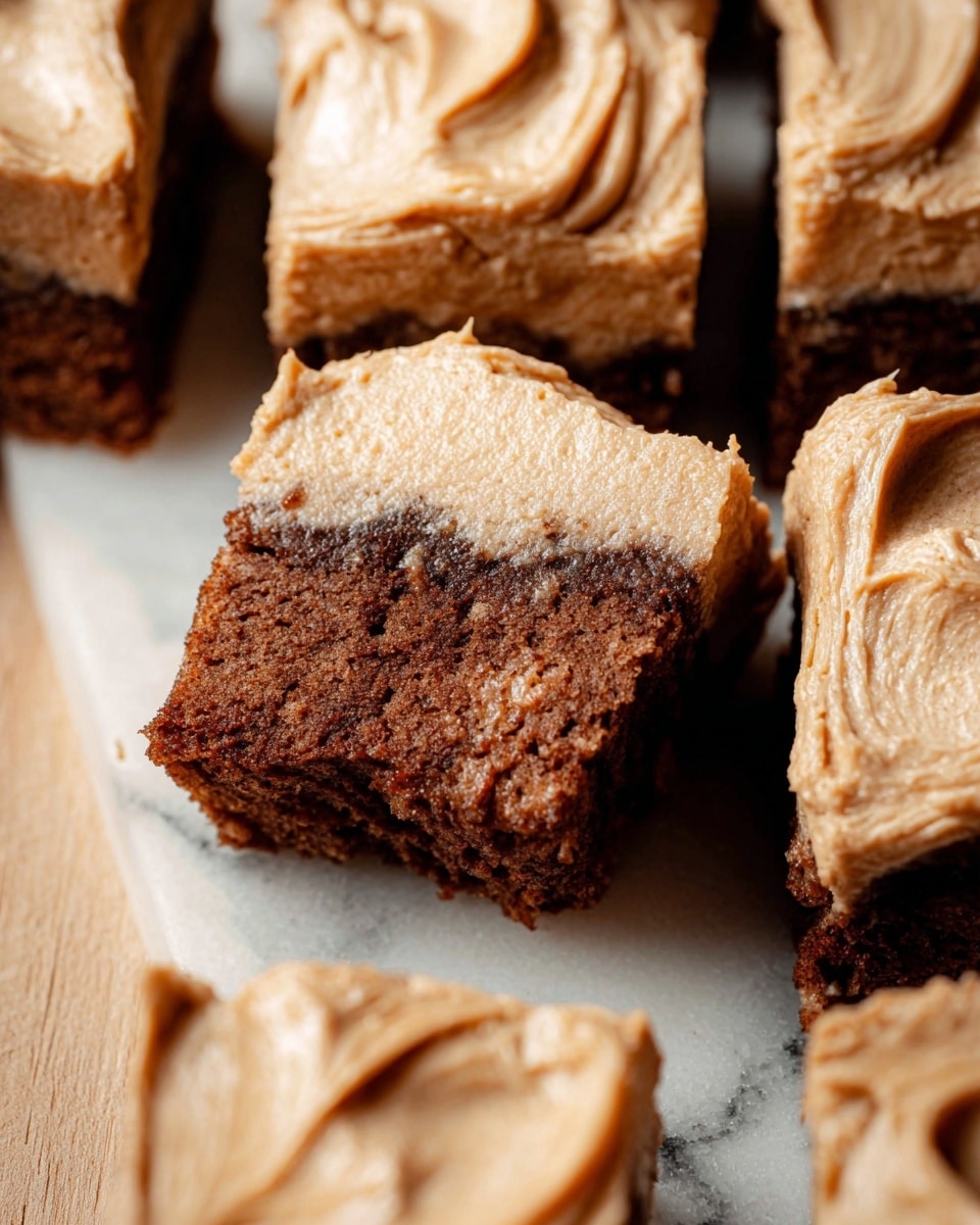 A close-up image of multiple thick square cake slices arranged on a white marbled surface, each slice showing two layers: the bottom layer is a moist brown cake with a soft, crumbly texture, and the top layer is a thick, creamy frosting in a light brown color with visible swirls and ridges that give it a smooth, fluffy look; one slice is partially eaten, revealing the dense inside of the cake. Photo taken with an iphone --ar 4:5 --v 7