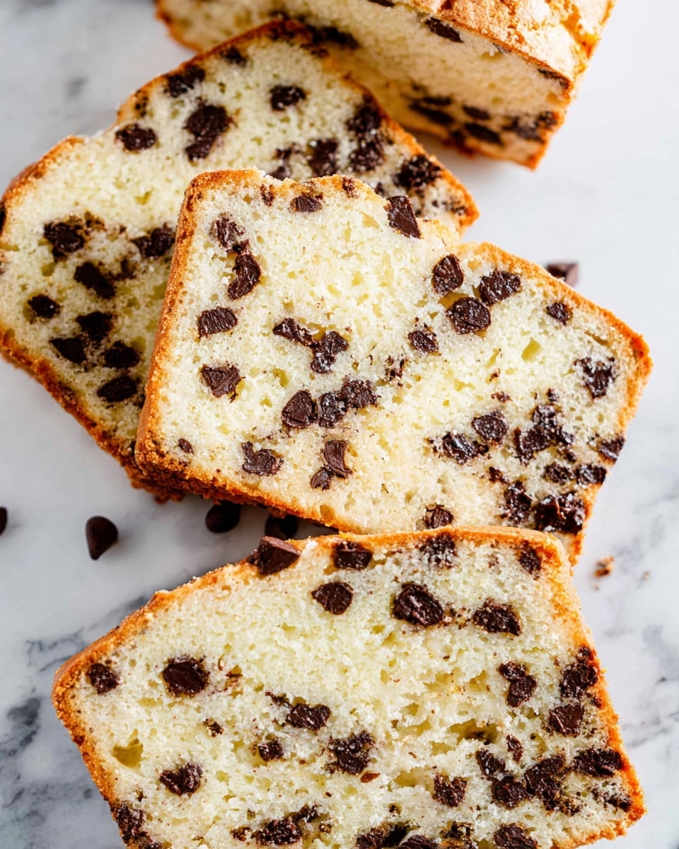 A close-up view of five slices of chocolate chip bread arranged casually on a white marbled surface. The bread has a light golden-brown crust with a soft, pale yellow crumb inside, filled generously with irregular-sized dark brown chocolate chips scattered evenly throughout. The texture looks moist and slightly crumbly, with some crumbs visible around the edges. The slices are stacked and overlapping, showing both the top crust and the inner soft parts clearly. photo taken with an iphone --ar 4:5 --v 7