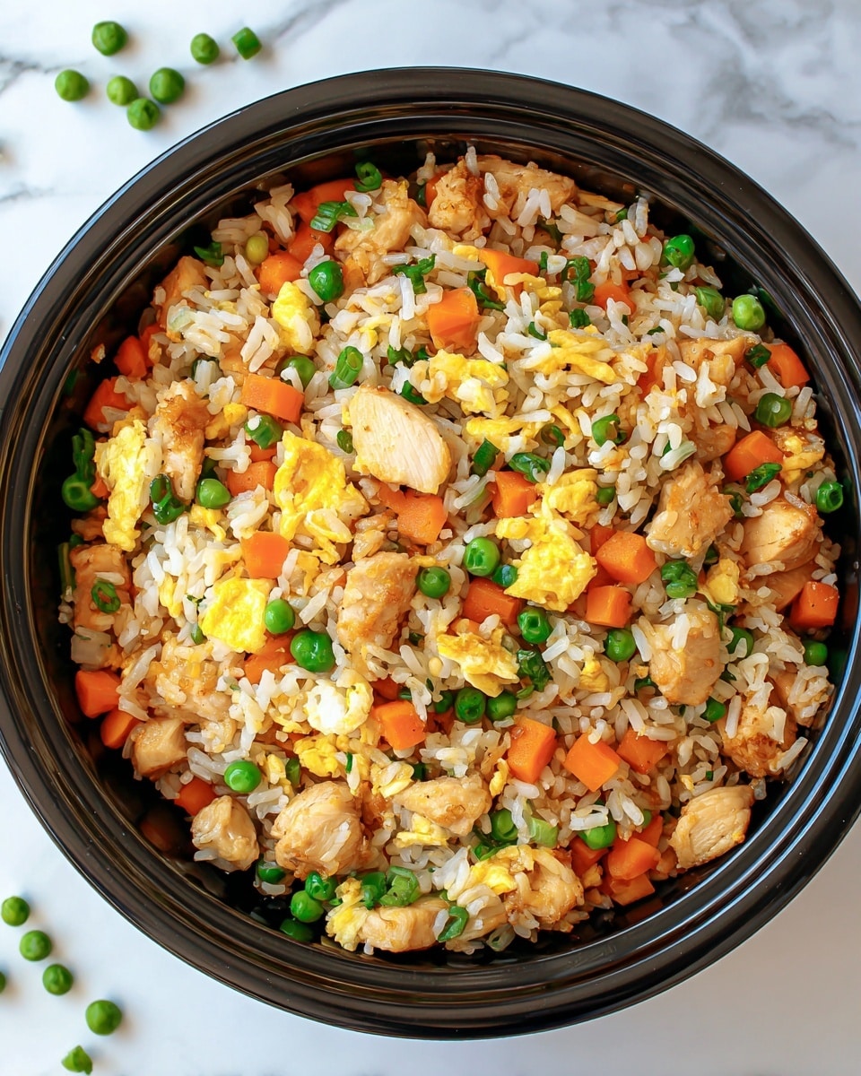A round black bowl filled with fried rice showing a mix of white rice grains, diced bright orange carrots, green peas, small yellow scrambled egg pieces, and light brown cooked chicken chunks. The ingredients are evenly spread and mixed, creating a colorful and textured look. The bowl is placed on a white marbled surface with a few scattered peas nearby. photo taken with an iphone --ar 4:5 --v 7