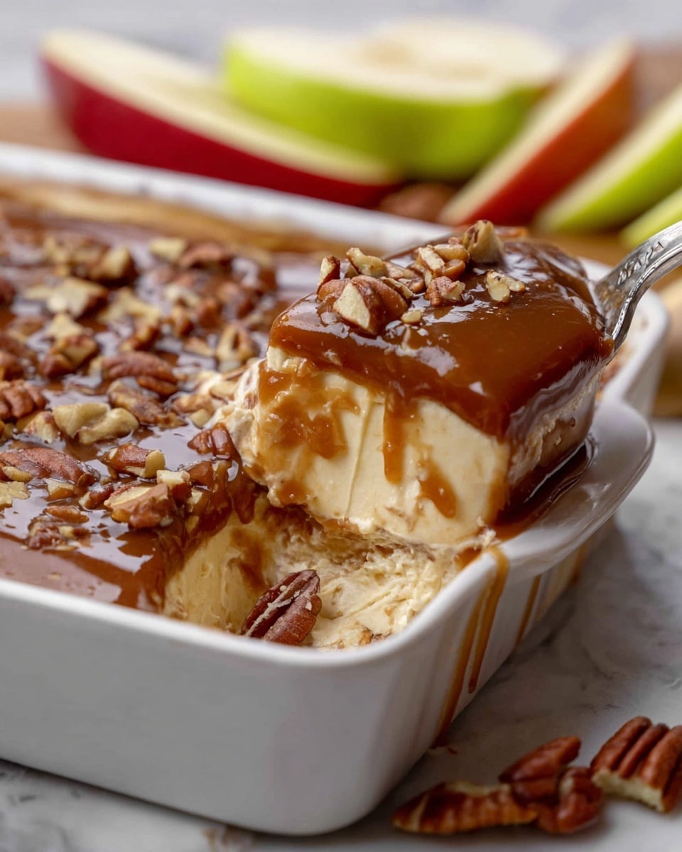 The image shows a close-up of a layered dessert in a white rectangular dish placed on a white marbled surface. The dessert has three visible layers: the top layer is a smooth, shiny dark caramel-colored sauce sprinkled with chopped pecans, the middle layer is creamy and light beige in color with a soft texture, and the bottom layer is slightly visible but appears to be thick and light cream-colored. A spoon is scooping out a portion, mixing the middle creamy layer and the caramel sauce with pecans. Around the dish, there are fresh apple slices in green and red colors, adding a fresh touch to the scene. photo taken with an iphone --ar 4:5 --v 7